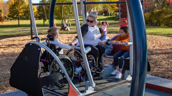2 people in wheelchairs playing on inclusive playground equipment