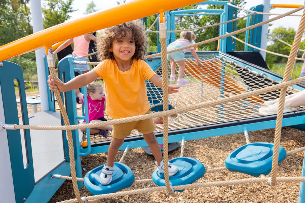 Child playing on climber with blue pods.